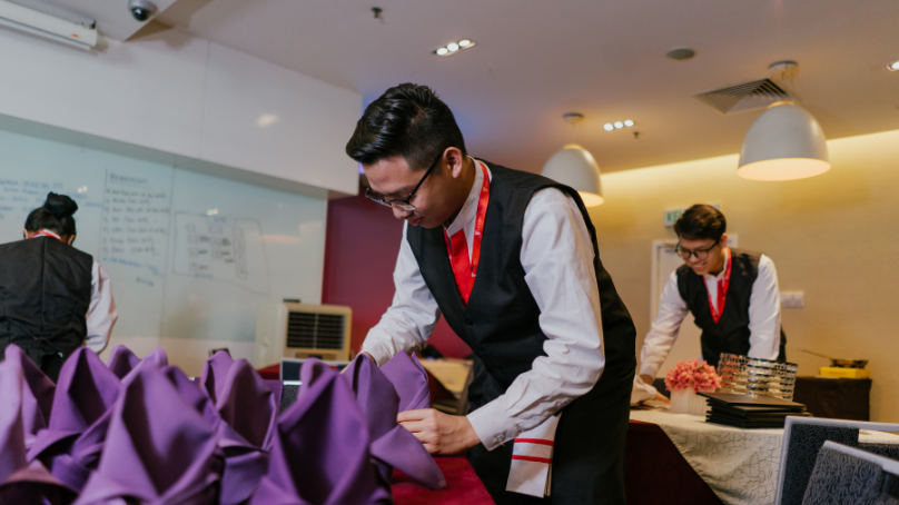 a hospitality student fixing up a dining table