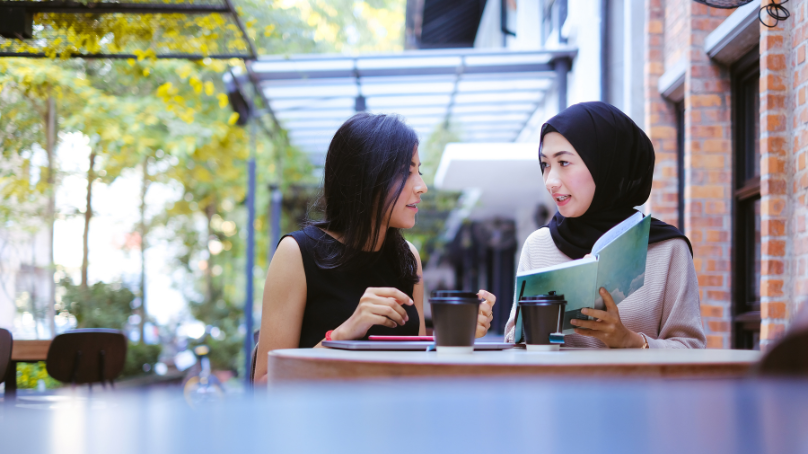 2 women talking about a book in a cafe
